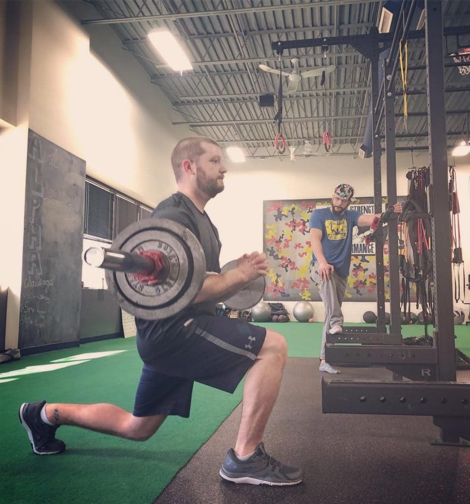 Bob doing split squats under the watchful eye of a personal trainer at beyond strength performance in sterling, virginia