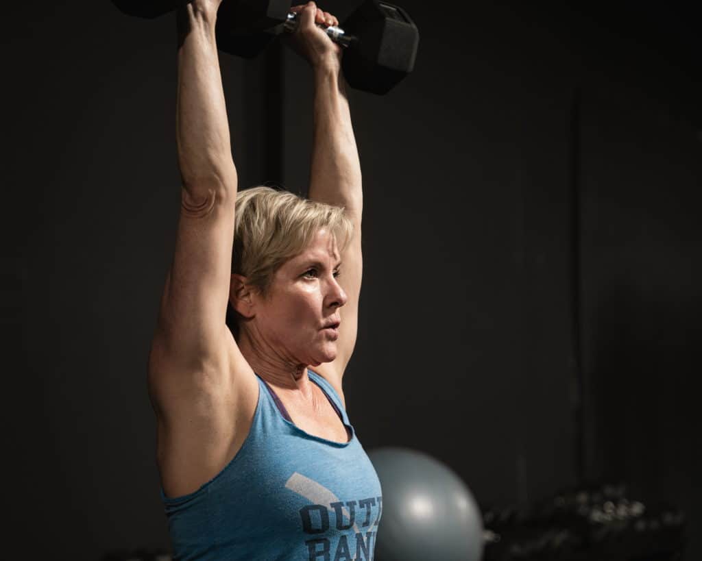 Libby doing overhead presses during a muscle growth phase of training at Beyond Strength gym in Sterling, VA