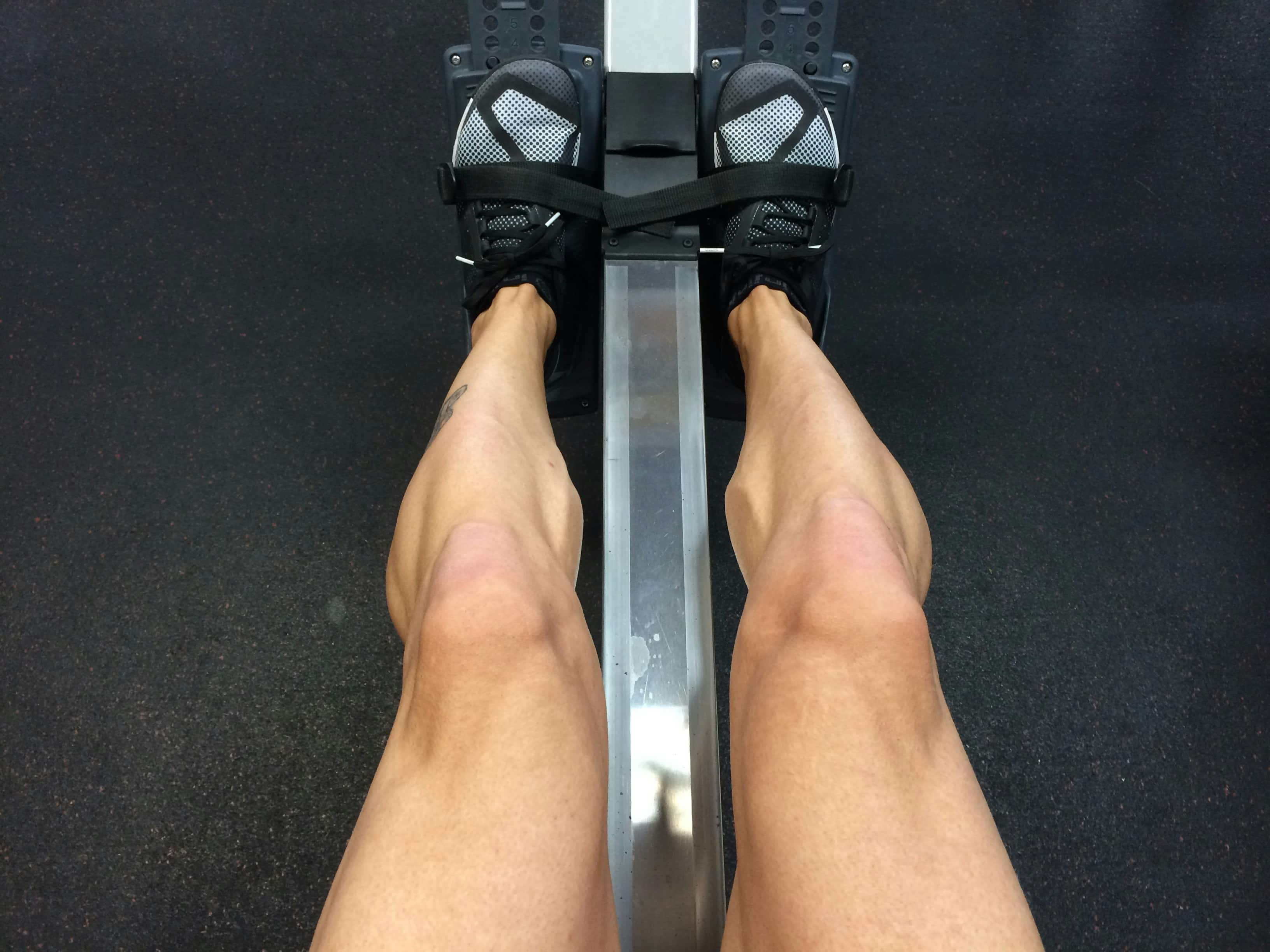 Close-up of an athlete's legs using a Concept2 rower during a strength and endurance workout.